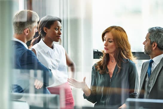 Four people having an impromptu meeting while standing up in a workplace